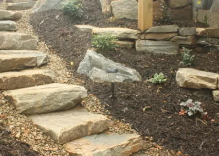 Natural stone steps with boulder edging, mulch beds, and hillside plantings